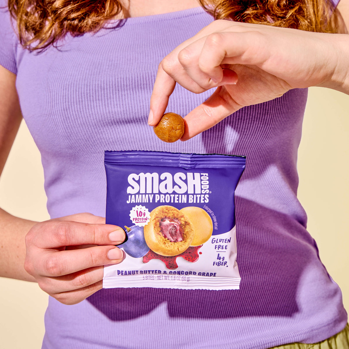 Hand pulling a bite from a PB Grape bag