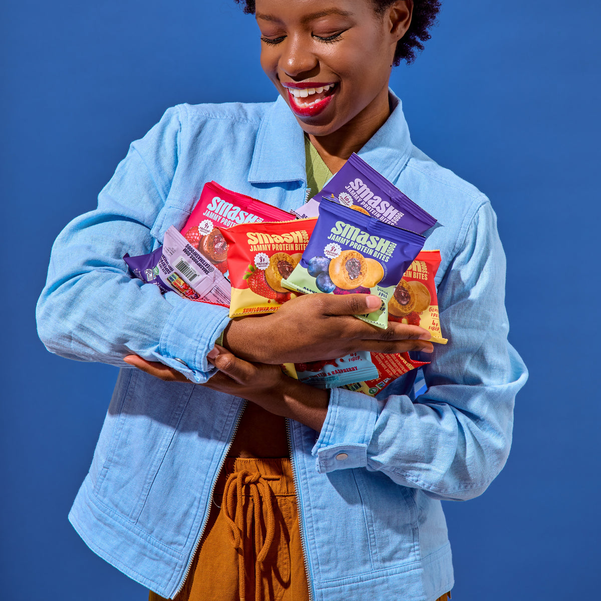 Woman hugging an armful of Smash Jammy Protein Bites bags